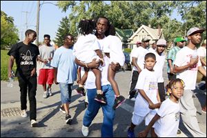 Paul Parker, a former member of X Blocc, a Crips affiliated gang, holds his twins Payyon, left, and Paylin as he marches. Parker changed his life after going to prison on a drug charge. 