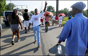 The Rev. Chris McBrayer, left, inspires the crowd as they walk down North Detroit during the march to end gang violence. Mr. McBrayer is a former gang member.