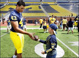 Whitmer graduate and Michigan defensive end Chris Wormley signs an autograph for  Camden Dings, 7, of Toledo, during the recent Fan Day. He is likely to see plenty of playing time this season.