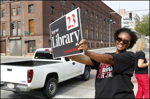 Pauline Kynard holds up a sign for a 2012 library levy campaign during a kickoff event in front of Fifth Third Field in September of that year.