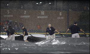 Comerica Park grounds crew members pull the tarp across the field as rain falls during the seventh inning Friday in Detroit.