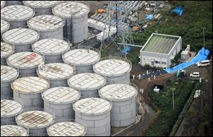 Workers stand on storage tanks at the Fukushima Dai-ichi nuclear plant at Okuma town in Fukushima prefecture, northeastern Japan, on Aug. 20.