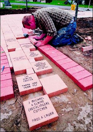 Quincy Hens of Landscape Design Inc., installs a walkway in the commemorative garden.