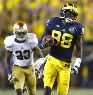 Michigan quarterback Devin Gardner outraces Notre Dame's Lo Wood for a first down during the second quarter Saturday night at Michigan Stadium in Ann Arbor.