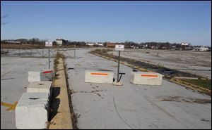 Concrete blocks and a partial gate prevent cars from entering the grounds of the former Southwyck Mall.