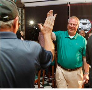 Cornelius Collins high-fives his first cousin D. Michael Collins after the mayoral candidate captured second place in Tuesday's mayoral primary.