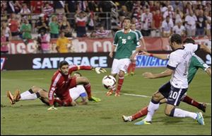 United States' Landon Donovan, right, scores a goal as Mexico goalkeeper Jose de Jesus Corona watches during the second half of a World Cup qualifying soccer match Tuesday in Columbus.