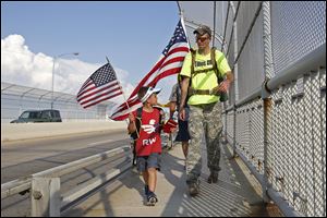 Army veteran Michael Lattea, right, crosses the Maumee River with Tim Willoughby, 6, left, and fellow veteran Brian Stark, not pictured.