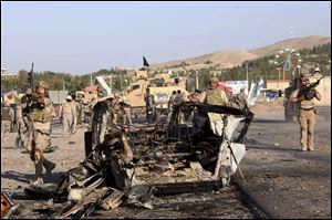 U.S.-led troops investigate the site of a suicide car bombing and a gunfight near the U.S. consulate in Herat Province, west of Kabul, Afghanistan today.