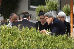 U.S. Secretary of State John Kerry, second right, and Russian Foreign Minister Sergey Lavrov, back to camera, talk, with their senior aides seated by a swimming pool at a hotel today in Geneva Switzerland.