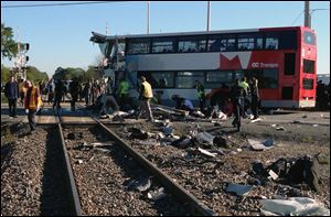 Officials respond to the scene where a city bus collided with a Via Rail passenger train at a crossing in Ottawa, Ontario, Wednesday, Sept. 18, 2013. An Ottawa Fire spokesman told CP24 television there are multiple fatalities and a number are injured from the bus but no injuries on the train.