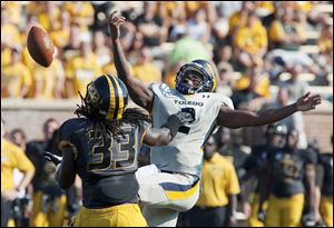 Missouri's Markus Golden, left, reaches to intercept the ball that slipped out of Toledo quarterback Terrance Owens' hand, right, before returning it for a touchdwon during the third quarter of an NCAA college football in Columbia, Mo.