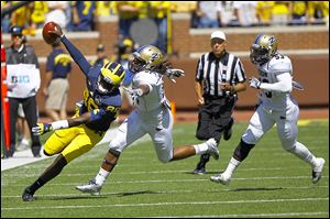 Michigan quarterback Devin Gardner tries to get past Akron's C.J. Mizell, center, and Jatavis Brown in last week's game. Gardner said he's not sure why the Wolverines have struggled on the road recently.