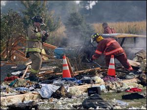 Firefighters search through debris after an explosion at a home on County Road 9, near County Road S, near Liberty Center.