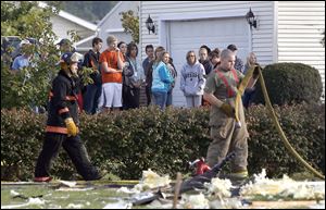 Neighbors watch as firefighters search through the rubble of a home in Liberty Township, near Liberty Center, Ohio. A school bus was 200 feet away from the house when the building exploded.