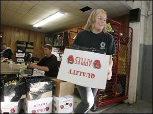 Kristi Hoffman of Grand Rapids carries a box of peeled apples so they can be cut. Behind her is Neil Box, who can peel and core a bushel of apples in five minutes. 