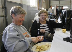 Valerie Rickenberg, left, and Mary Loeffler, both of Grand Rapids, cut up peeled apples for some of the thousands of pints of apple butter expected to be sold during the town’s annual festival next month. 