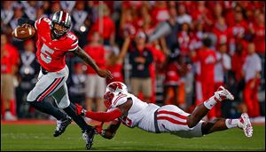 Ohio State quarterback Braxton Miller eludes Wisconsin's Warren Herring in Saturday's game. Miller threw for four touchdowns in his return from injury.