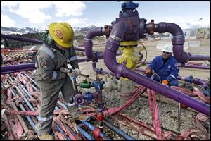 Workers tend to a well head during a hydraulic fracturing operation at an Encana Oil & Gas Inc. gas well outside Rifle in western Colorado.