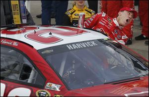 Driver Kevin Harvick climbs out of his race car in victory lane after winning the  NASCAR Sprint Cup series race Sunday at Kansas Speedway in Kansas City, Kan.