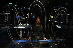 A  museum employee poses by a display of rubies, pearls, amethysts and diamonds chains.