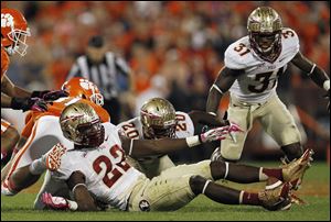 Clemson tight end Stanton Seckinger looks for a fumbled ball with Florida State linebacker Telvin Smith (22), defensive back Lamarcus Joyner (20) and defensive back Terrence Brooks (31) during the first half Saturdayin Clemson, S.C. Florida State recovered the loose ball, which is between Smith's feet.