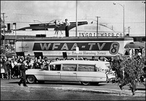 In this Nov. 22, 1963 file photo, people line the street as the hearse bearing the body of slain U.S. President John F. Kennedy drives past a television truck as it leaves Parkland Hospital in Dallas, to be flown to Washington.