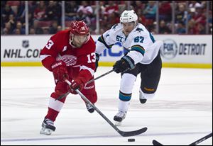 Detroit Red Wings forward Pavel Datsyuk (13), of Russia, reaches for the puck, defended by San Jose Sharks forward Tommy Wingels (57), during the first period of an NHL hockey game in Detroit, Mich., Monday, Oct. 21, 2013. (AP Photo/Tony Ding)