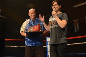 Harry Cummins, Executive Director of IBC, hands boxing gloves to Jodi Szczublewski of Clear Channel, as a thank you for their sponsorship and participation.