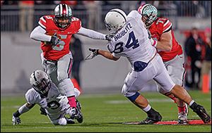 Ohio State quarterback Braxton Miller, left, escapes the grasp of Penn State's Jordan Lucas, bottom, and Kyle Baublitz during the first quarter.