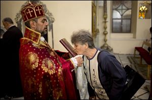 In this photograph made on Sunday, Oct. 27, 2013, a woman kisses the Bible during a service in an Armenian Orthodox church in Damascus, Syria.