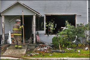 Firefighters work on examining the remnants of two-story structure after a fire on Fassett Street. Crews found two bodies while fighting the blaze.