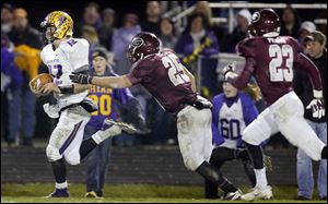 Bryan quarterback Austin Schimmoeller, left, breaks away from Genoa’s David Nutter to score a fourth-quarter touchdown. He ran for 124 yards and three touchdowns, and he completed 18 of 33 passes for 336 yards and three more scores. 