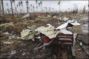 A young survivor uses the remains of some parts of a house to shield him from rain in Tacloban city, Leyte province, central Philippines.