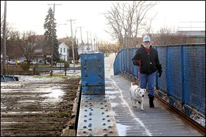 Ammy Matthews, of South Toledo walks her 5-year-old 'pit bull,' Ava, over a bridge to visit her grandfather. Council voted to raze the bridge spanning railroad tracks in the city’s Old South End.