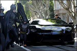 Miles Scott, dressed as Batkid, second from left, exits the Batmobile with Batman to save a damsel in distress in San Francisco today.