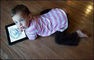 Reagan Zaal, 2, colors with an iPad at her home in Middletown, Md. More parents are looking for tablets for their children who have become accustomed to smart phones, iPads, and Kindles.