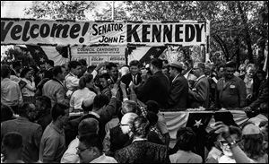 Above, John F. Kennedy is greeted by an enthusiastic Toledo crowd in 1959. During that visit, he urged Toledo to support a strong-mayor form of government — a local issue at the time. That form of city government was not adopted until the early 1990s. At right, Mr. Kennedy waves to onlookers after landing at Toledo Express Airport during his 1960 campaign trip here. 