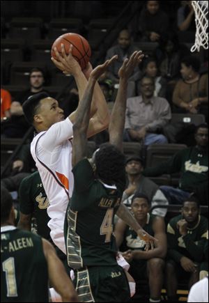 BGSU's JD Tisdale goes over South Florida's Corey Allen Jr. for two points during basketball game at the BGSU Stroh Center in Bowling Green.