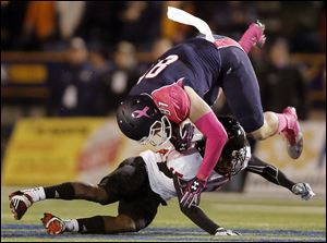 Toledo tight end Alex Zmolik makes a catch  before being tackled by Northern Illinois’ Jimmy Ward on Wednesday at the Glass Bowl.