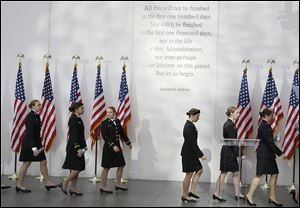 The U.S. Naval Academy Women’s Glee Club walks under a passage from President John F. Kennedy’s inaugural address before a ceremony on the 50th anniversary of his assassination at the John F. Kennedy library in Boston.