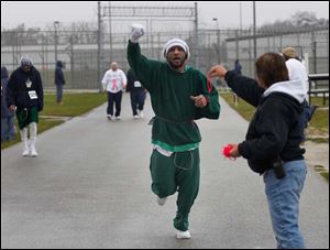 Toledo Correctional Institute inmate Steve James lifts his arm up in celebration of completing another lap during a 5K fundraiser for the Komen Foundation. He is reaching for a wristband marking his laps from case manager Terrie Janowski.