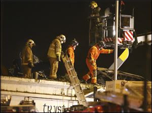 Firefighters and rescue workers inspect the damage at the site of a helicopter crash, in Glasgow late Friday night.