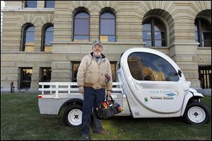 Gary Rogolsky, a maintenance worker at the Lucas County Courthouse, stands next to one of the electric-powered vehicles he uses to move between the county’s 12 downtown Toledo buildings.