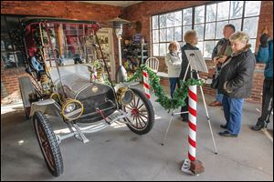 Eileen Angell reads about the 1910 Metz Plan Car that is on display at a home on Parkwood Avenue. The home is among eight structures included in the Tours de Noel, a fund-raiser for the Women of the Old West End.