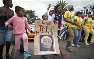 A young girl with a placard showing the face of Nelson Mandela and referring to his clan name 