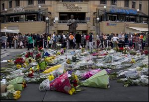 Floral tributes to former president Nelson Mandela, pile up beneath a statue of Mandela on Mandela Square at Sandton City, in Johannesburg today.