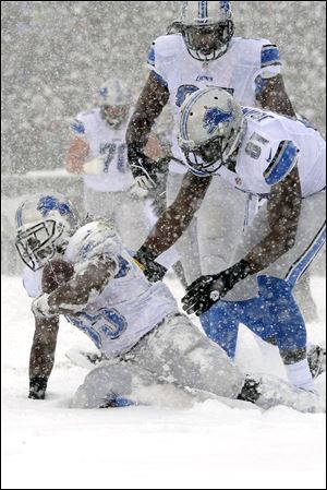 Detroit Lions' Joique Bell, left, gets up with the help of Brandon Pettigrew, center, and Calvin Johnson after scoring a touchdown during the first half.