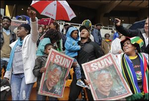 People hold images of  former South African president Nelson Mandela ahead of his memorial service.