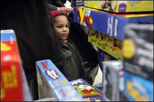 Da’Von Hicks, 4, gazes at a pile of games, above, during the Salvation Army’s annual Christmas distribution at the United Auto Workers Local 12 hall.  Families who applied and were approved in October and November collected toys Wednesday  for their children, as well as a holiday food basket.